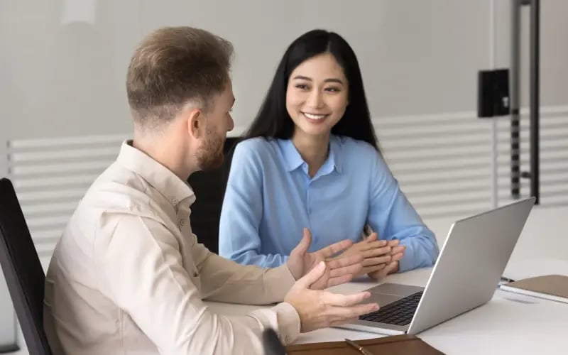 Manager and employee discussing career growth at a desk with an open laptop in a modern office.