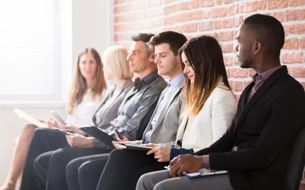 Professionally dressed job seekers wait in a corporate lobby for an interview.