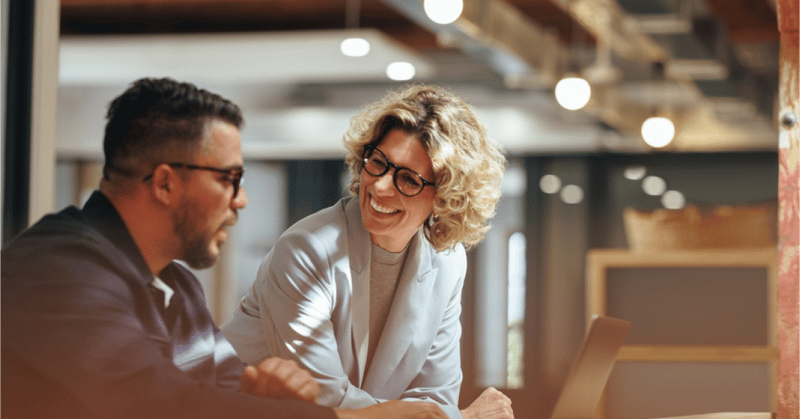 Two business professionals discussing outplacement solutions at a table with a laptop.
