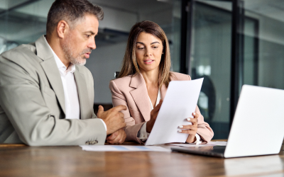 An individual impacted by layoffs receives outplacement support, mitigating the emotional toll of job loss. During an outplacement coaching session, the coachee shows their coach a resume and receives advice on improvements while a laptop is open in front of them.