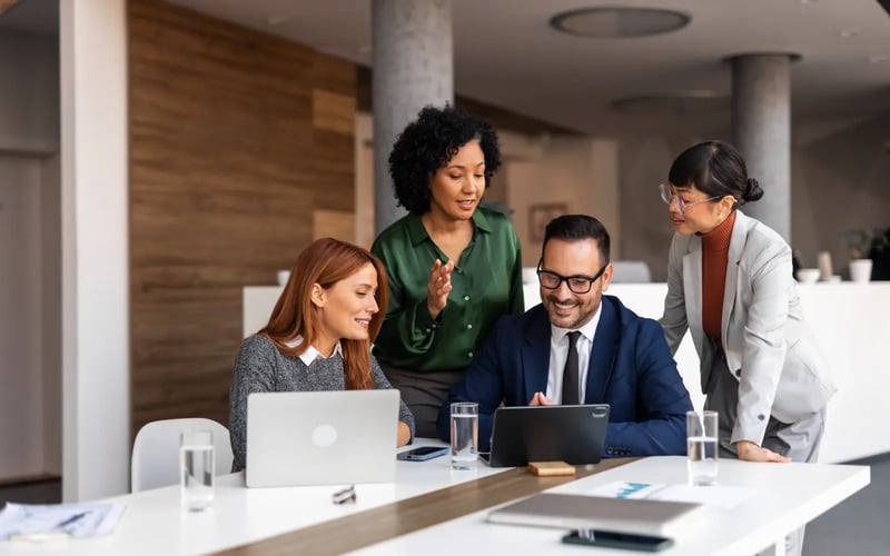 Engaged employees collaborate with laptops and tablets, reflecting strong career mobility through restructuring. 