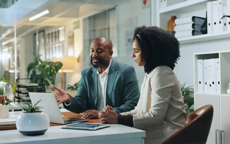 Outplacement coach works with a coachee at a desk to support career transition and preserve a talent network after layoffs. 