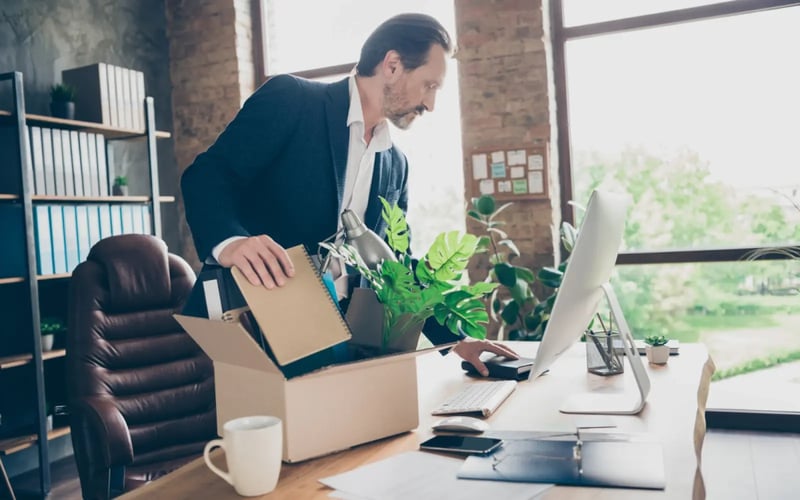 A C-suite executive puts office materials in a box as he prepares for executive outplacement. 