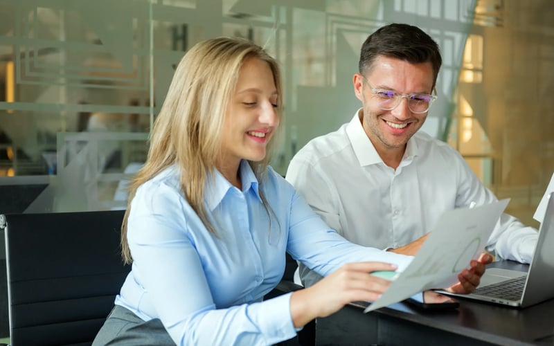 Two HR professionals collaborate on a talent mobility strategy with a laptop open.