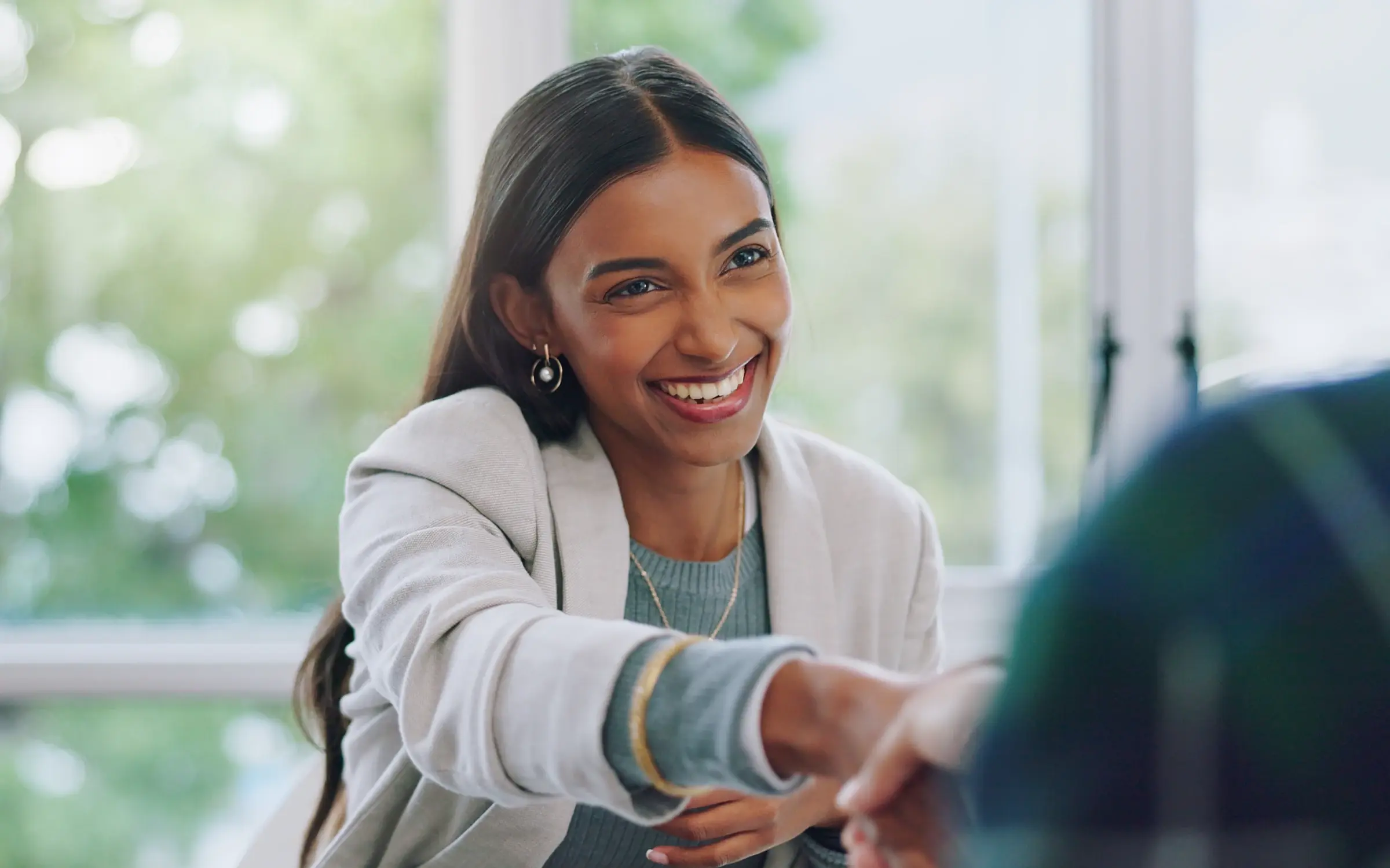 After applying job hunting tips, a woman confidently shakes hands with a hiring manager to celebrate her new role. 