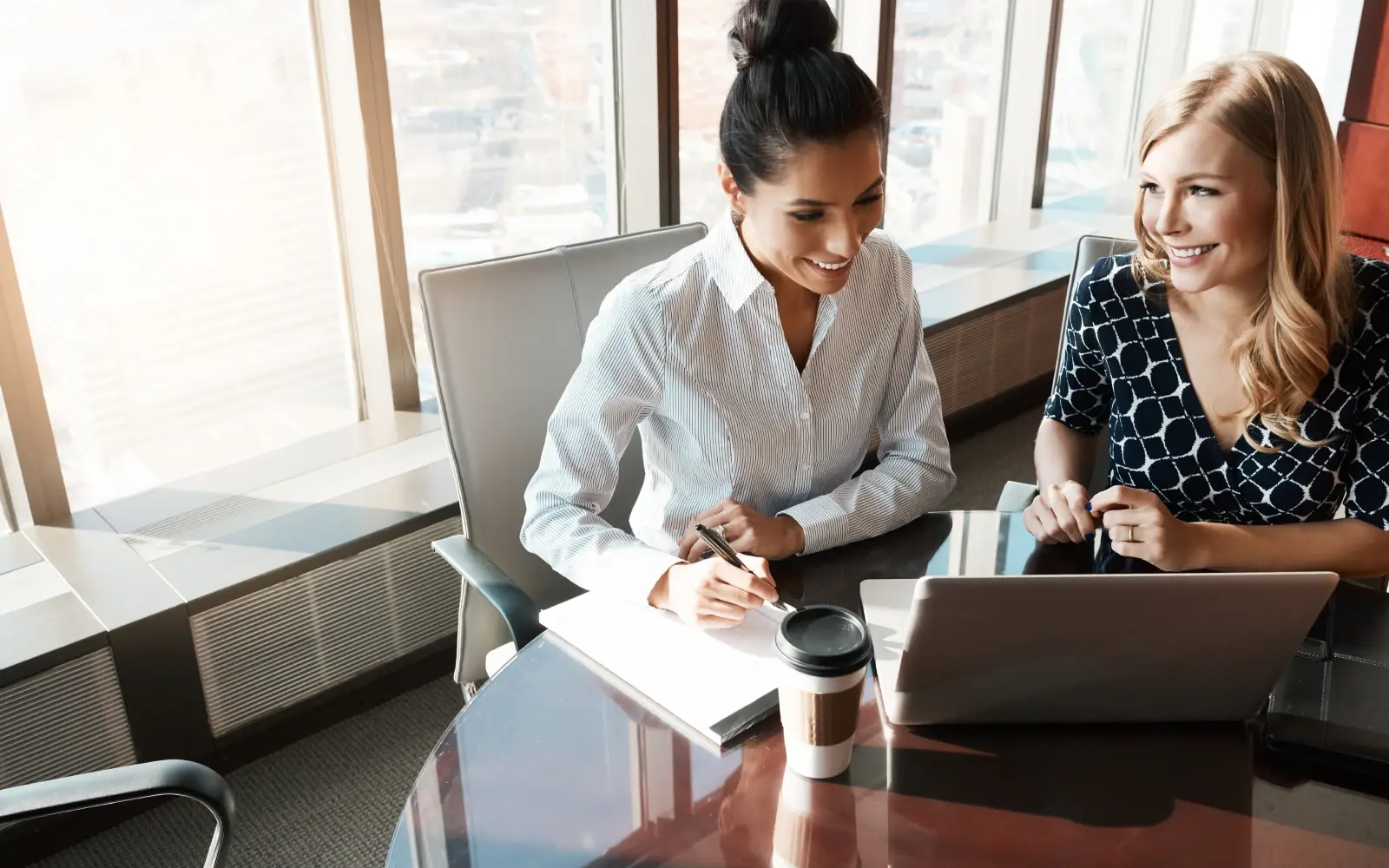 A woman in brown blouse is sitting at a desk providing employee outplacement services to a man in blue shirt. 